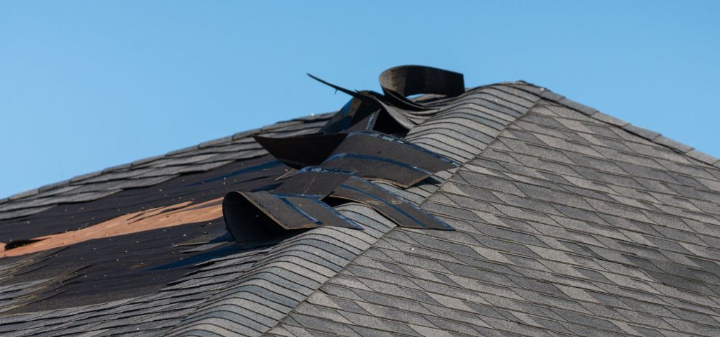 Roof shingles that have been lifted and damaged due to wind